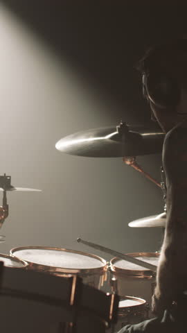 Romantic rock song, professional drummer beating rhythm on drum kit on stage, vertical video. Enjoy contemporary music style and feel emotions and power of modern music, stage light in darkness