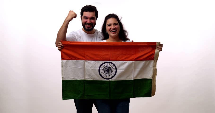 Couple with Indian national flag celebrating with fist and saluting proudly against white background, smiling and confident during Republic Day or Independence Day celebration, looking at camera
