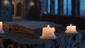 Cinematic shot of ancient candles flickering beside old book on textured rock surface, with cold, enchanted blue light pouring through windows in fantasy stone chamber. - Powered by Shutterstock - Get 15% off with code: PIKWIZARD15