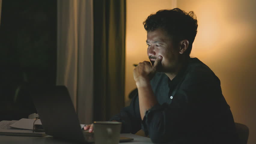 Asian man puts on his glasses to resume working late at night.4k