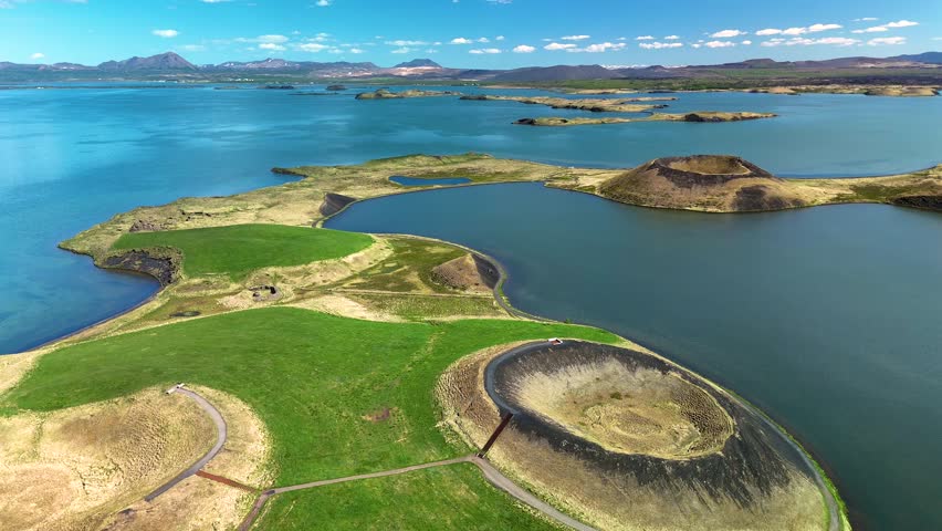 Discover the enchanting beauty of Icelands unique geography featuring volcanic craters, lush greenery, and tranquil Myvatn lake waters under a clear blue sky. Ideal for nature lovers seeking adventure