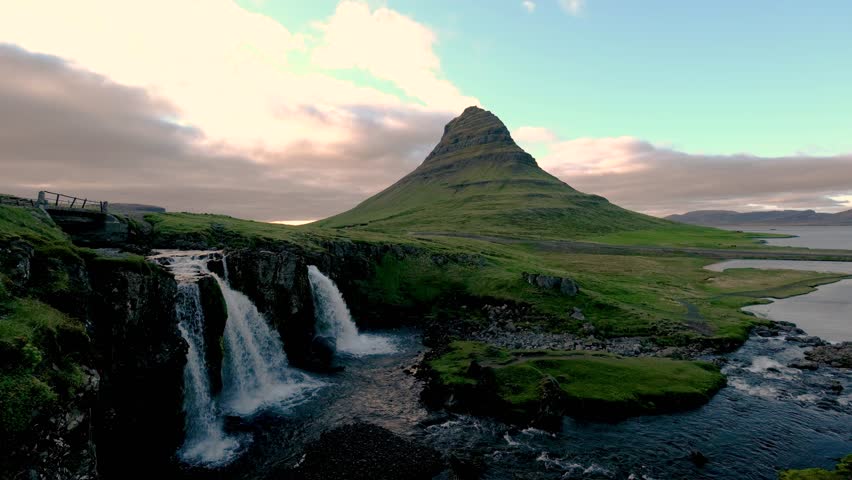 Experience the breathtaking beauty of Kirkjufell mountain and its stunning waterfall. This serene Icelandic landscape showcases vibrant colors during sunset, creating a magical atmosphere.