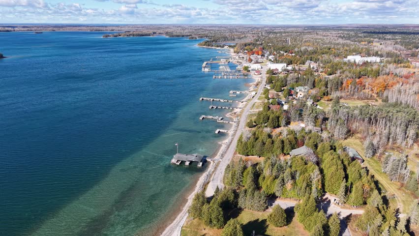 Aerial view of Hessel, Michigan showing marina, shoreline, and fall foliage along the Lake Huron coast in the Upper Peninsula
