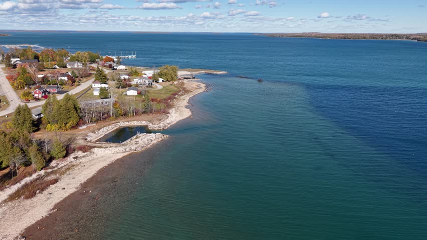 Aerial view of a small lakeside town along Lake Huron with clear blue water and rocky shoreline in Michigan’s Upper Peninsula