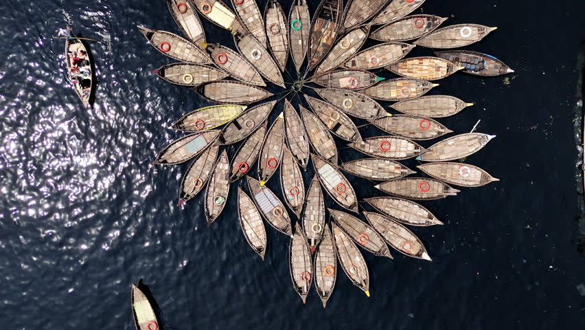 Beautiful cinematic drone shot of traditional wooden ferries docked together on the Buriganga river in Dhaka, Bangladesh, downward angle shot