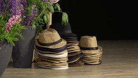 Stacks of straw fedoras in multiple shades neatly arranged on a wooden floor beside tall flower pots with blooming lupines. Indoor setup with copy space.
 - Powered by Shutterstock - Get 15% off with code: PIKWIZARD15