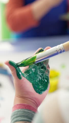 Student, child and painting on hand in classroom for creative project, art lesson and coordination skills. Kindergarten, closeup and paintbrush for messy color artwork, education or motor development