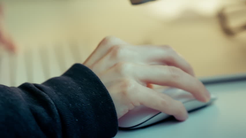 home studio working on computer  hand holding mouse typing on keyboard white table laptop
