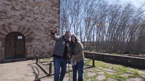 Happy couple taking selfies with phone and hiking poles in front of old building - Powered by Shutterstock - Get 15% off with code: PIKWIZARD15