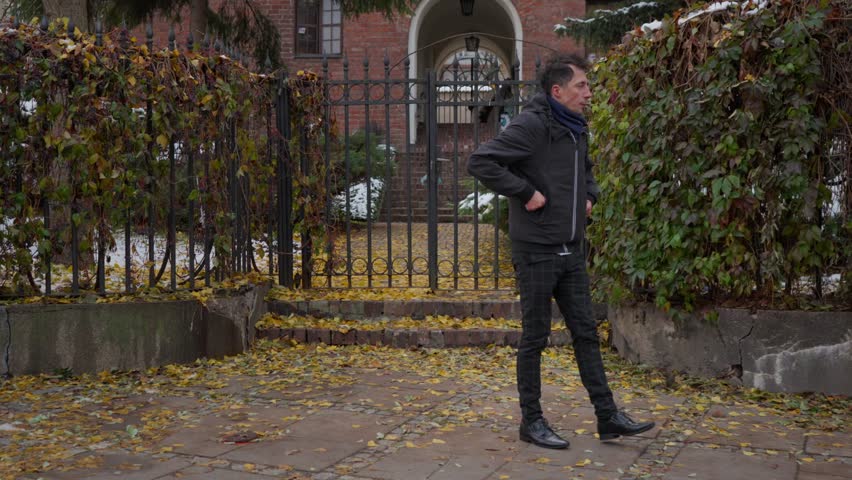 A man waiting for an appointment on a cold late autumn day tries to stay warm. He paces back and forth and rubs his hands together, feeling the chill while he waits for someone.