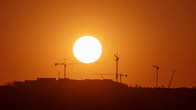 Sunset silhouette time lapse of construction site with cranes. Building and industry scene capture on telephoto lens. - Powered by Shutterstock - Get 15% off with code: PIKWIZARD15