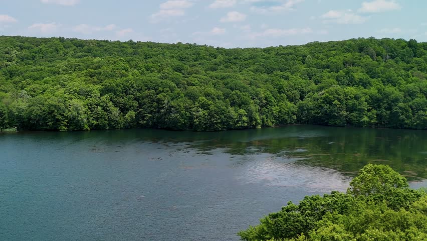 Serene lake nestled within a lush forest, surrounded by towering trees and vibrant greenery, creating a peaceful and natural retreat. Aerial slow-motion footage of Crescent Lake in USA.
