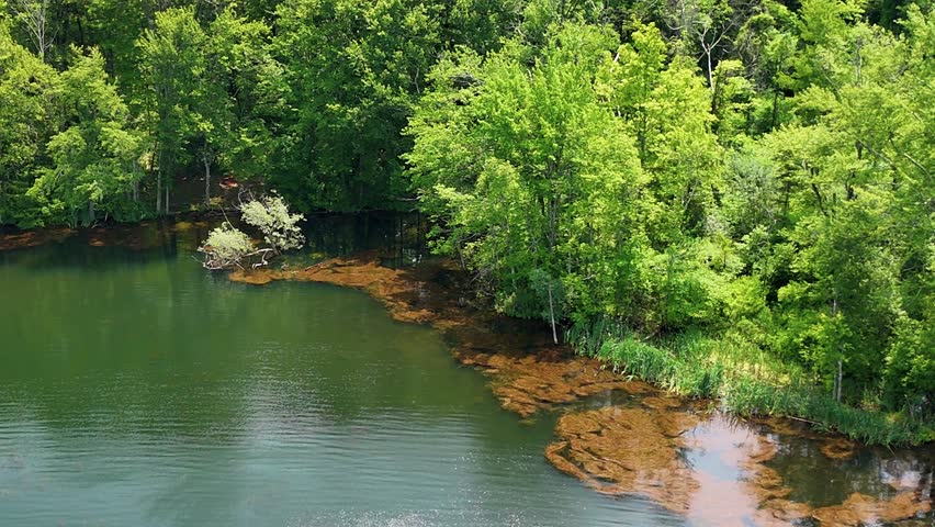 Crescent Lake in Southington, Connecticut, USA. Surrounded by lush green forest and calm waters, the area is ideal for fishing, kayaking, and hiking. Aerial slow-motion shot.