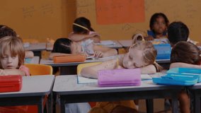 Boy writing in classroom pausing to view poster with chalk equations animating during math exercise. Education, school, learning, childhood, classroom, concentration, collaboration - Powered by Shutterstock - Get 15% off with code: PIKWIZARD15