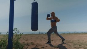 A middle-aged man kicks a punching bag on a playground near the sea - Powered by Shutterstock - Get 15% off with code: PIKWIZARD15