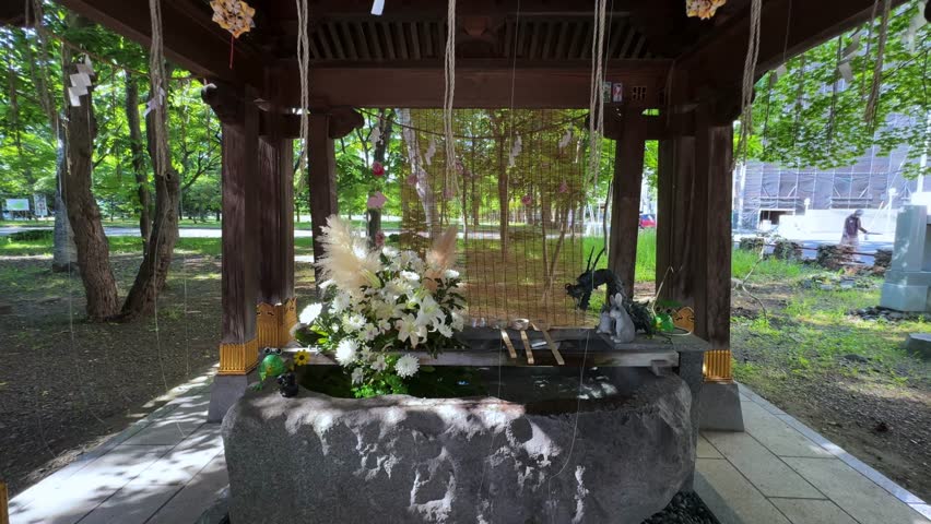 Flower arrangement with figurines, stone basin, and greenery in Sapporo park