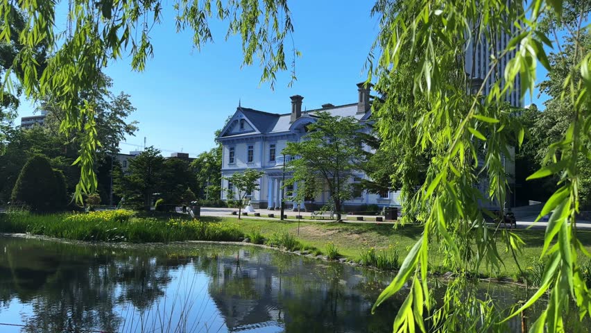 Scenic view of Sapporo Nakajima Park with a pond, lush greenery, and historic building