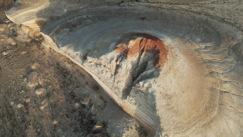 Circular formation with vivid earth layers filmed from the air. The deep eroded bowl near the Aral Sea stands as a geological monument in Uzbekistan