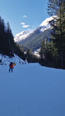 Winter season at Bansko ski resort in Bulgaria with a view to the skiers having fun on the slope and Pirin mountains in the background
