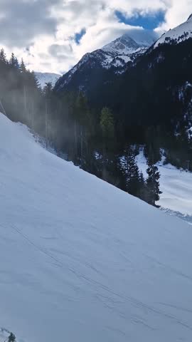 Aerial view to the snowy slope with freeride skiers having fun at Bansko ski resort in Bulgaria. Pirin mountains ridge in the background
