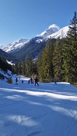 Winter season at Bansko ski resort in Bulgaria with a view to the skiers having fun on the slope and Pirin mountains in the background
