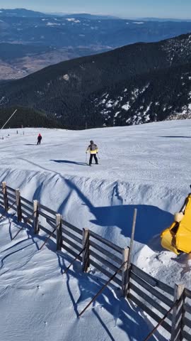 Aerial view to the snowy slope with skiers having fun at Bansko ski resort in Bulgaria
