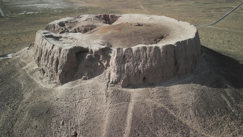 Worn mudbrick walls form a circle atop the Chilpik mound. Zoroastrian funerary monument overlooks the steppe. View shows scale of the sacred structure clearly