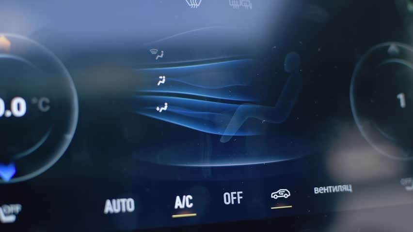 Driver adjusts digital climate control via touchscreen, selecting air conditioning and ventilation for perfect comfort inside modern car.