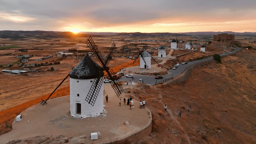 Aerial view of the historic windmills of Consuegra at sunset, Castilla-La Mancha, Spain. Old historic windmills of Don Quixote character on the hills in evening light. Molinos de Viento de Consuegra