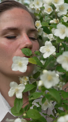 Woman Smelling Jasmine Woman with eyes closed smelling fragrant white jasmine flowers in nature enjoying scent