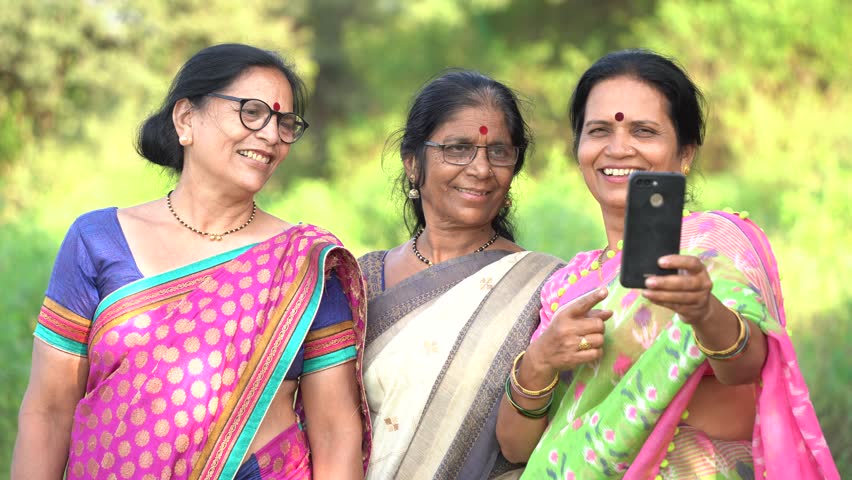 Happy rural women using mobile, India.