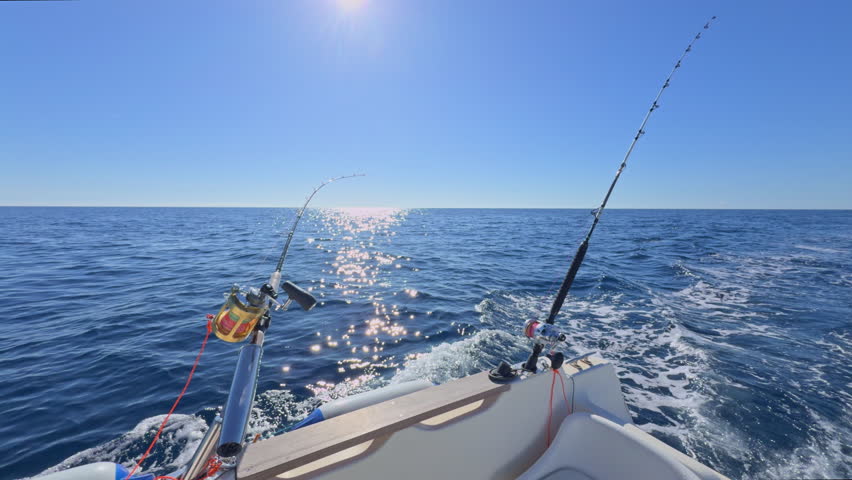 Sport boat trolling ocean with rods, reels, saltwater outboard fishing