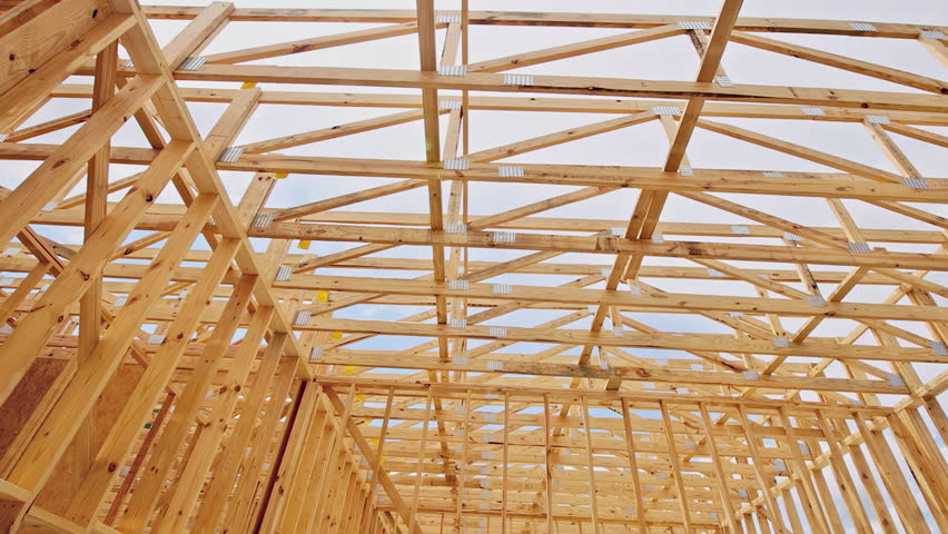 Workers focus on framing trusses wooden house, showcasing structure at construction area