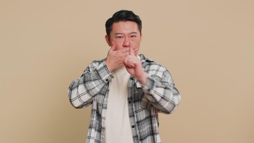 I will not say anything. Strict Asian middle-aged man closing mouth with hands, looking intimidated scared at camera gestures no refusing to tell terrible secret unbelievable truth. Mature Chinese guy