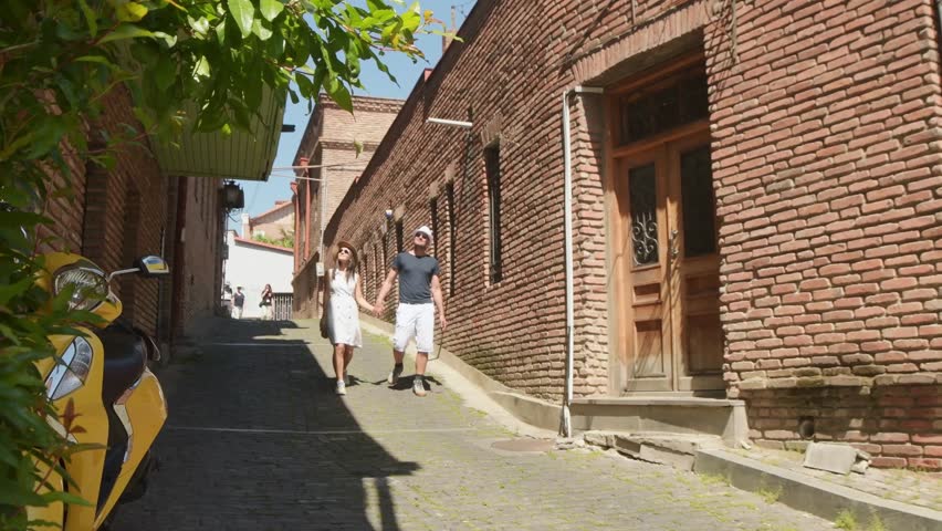 Tbilisi, Georgia - 27th may, 2025: Couple of tourists walking sightseeing old Tbilisi street at holiday - Happy friends laughing together on vacation - People and holidays concept. Travel in Georgia
