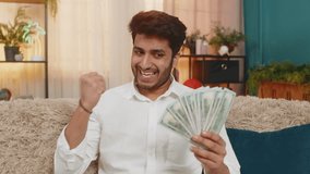 Indian man at home counting cash dollars, carefully considering his budget and planning future expenses. Arabian guy sitting on sofa, focusing on money management and thoughtful financial decisions - Powered by Shutterstock - Get 15% off with code: PIKWIZARD15