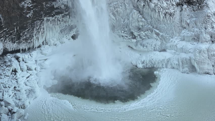 Snoqualmie Falls waterfall crashing into frozen splash pool with ice on rocky walls