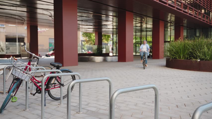 Mature man cycling with electric bicycle in the city enjoying sustainable mobility, parking bike near office