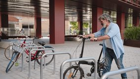 Mature man cycling with electric bicycle in the city enjoying sustainable mobility, parking bike near office - Powered by Shutterstock - Get 15% off with code: PIKWIZARD15