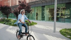 Happy active senior man cycling on city street riding foldable electric bicycle - Powered by Shutterstock - Get 15% off with code: PIKWIZARD15