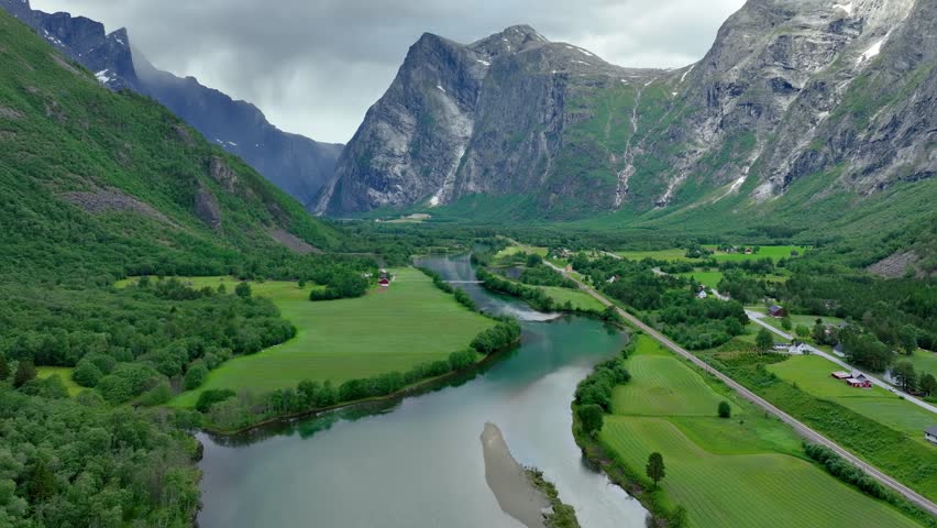 Aerial of the Rauma river winding through meadows and farmland in the Romsdalen Valley in Norway.