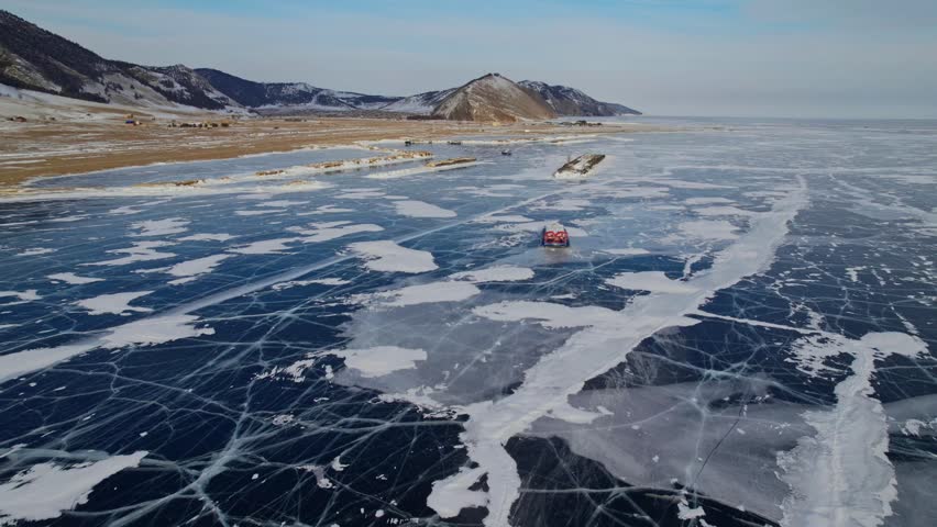 Drone panorama of vehicle crossing frozen lake Baikal with hovercraft in winter landscape, Russia.