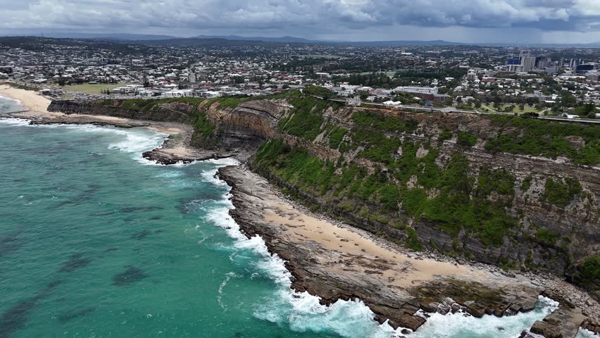 Newcastle NSW Australia Rocky Coastline Coastal Cliffside Overlooking the Ocean with Urban Skyline in the Distance. Shepherds Hill, the Hawkesbury Sandstone deposit on which Newcastle was built