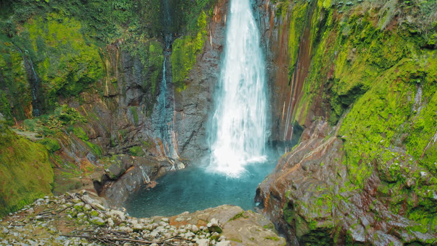 Powerful Catarata del Toro waterfall plunging into deep natural rocky basin in Costa Rica