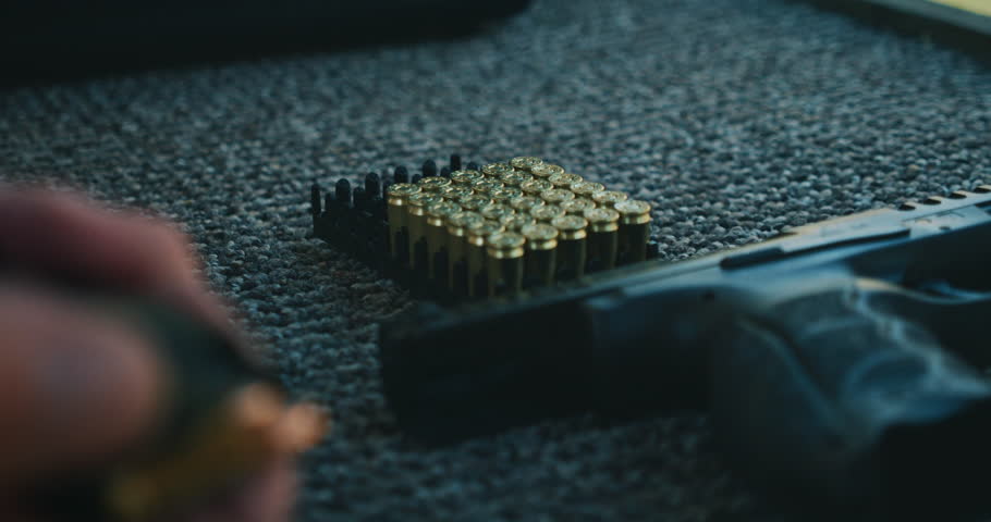 Hand loading handgun with box of brass bullets at shooting range training session