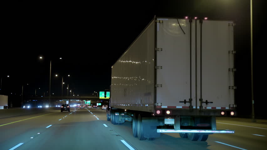 Driving close to the white truck trailer on highway at night time. Wide POV wide shot shot