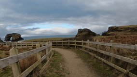 Coastal trail to Great Pollet Sea Arch in Donegal, Ireland. Gravel path with wooden fence, wild cliffs, and Atlantic Ocean under a dramatic sky. - Powered by Shutterstock - Get 15% off with code: PIKWIZARD15