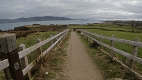 Coastal trail to Great Pollet Sea Arch in Donegal, Ireland. Gravel path with wooden fence, wild cliffs, and Atlantic Ocean under a dramatic sky. - Powered by Shutterstock - Get 15% off with code: PIKWIZARD15