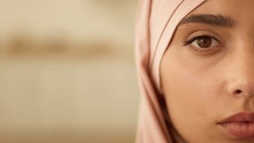 Close up health problem pensive peaceful half female face at home Muslim woman in hijab Islamic girl look Islamic lady Islam religion in headscarf looking at camera serious discrimination religion - Powered by Shutterstock - Get 15% off with code: PIKWIZARD15