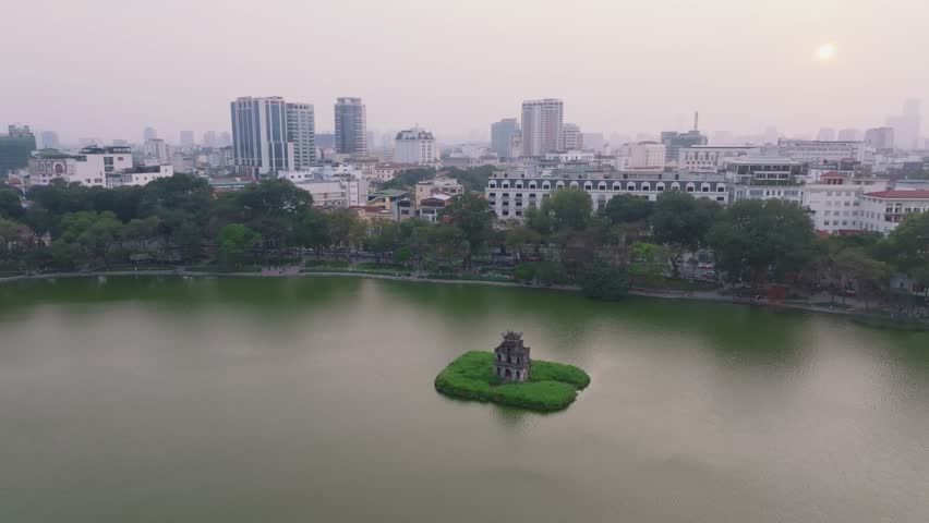Serenity at Hoan Kiem Lake during twilight hours in Hanoi, Vietnam with urban skyline backdrop